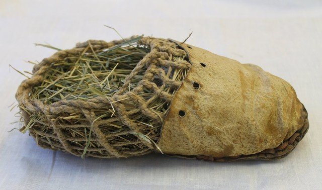 A shoe with leather tops and straw netting backing, stuffed with hay.